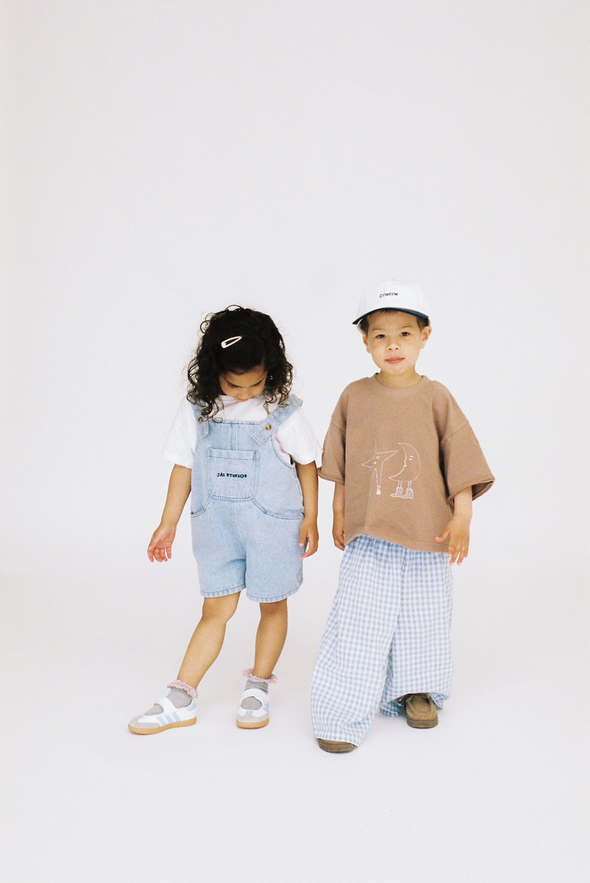 Jai Studios Lux Overalls in neutral fabric, featuring adjustable straps and a relaxed fit, displayed on a hanger.